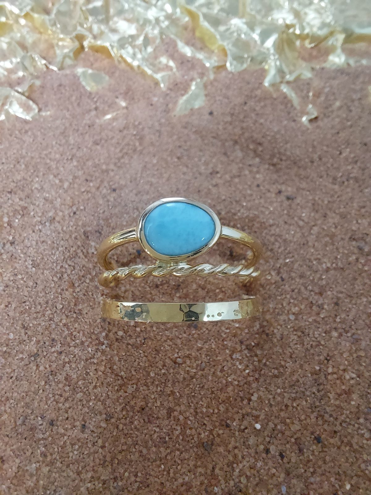 Bague en or sertie d'une turquoise, portée avec deux anneaux